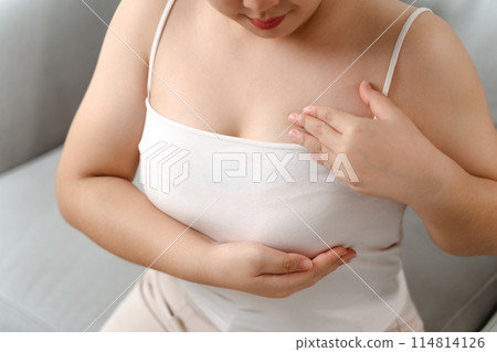 Asian woman checking lumps on her breast for signs of breast cancer by her self at home 114814126