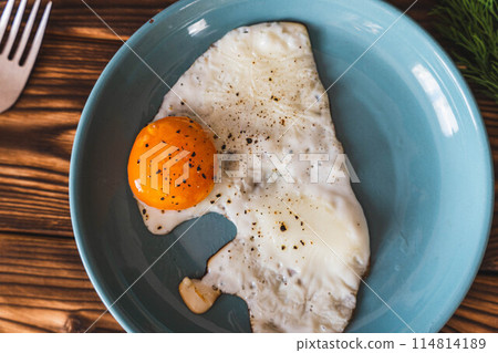 A plate with scrambled eggs and an egg atop, accompanied by a fork A plate with scrambled eggs and an egg atop, accompanied by a fork 114814189