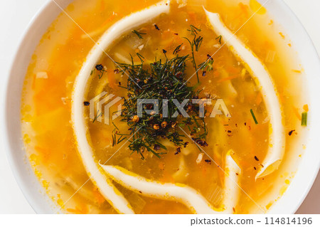A white bowl filled with delicious chicken soup garnished with herbs and mayonnaise 114814196