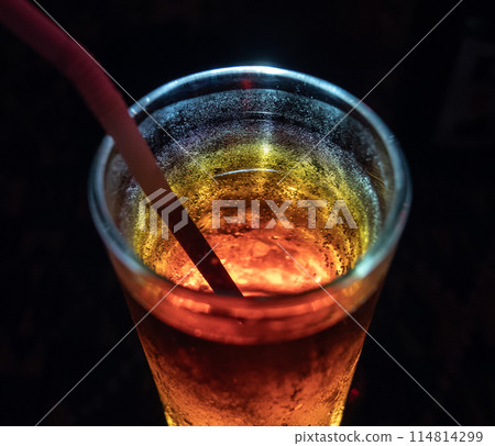 Close-up of refreshing chilled cocktail with straw in dimly lit bar at night 114814299
