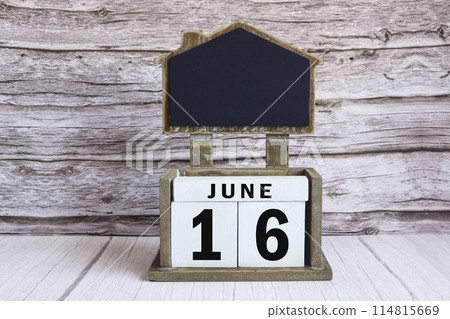 Chalkboard with June 16 date on white cube block on wooden table. Chalkboard with June 16 date on white cube block on wooden table. 114815669