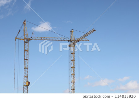 Two construction cranes against the blue sky, preparing for the construction of a high rise building Two construction cranes against the blue sky, preparing for the construction of a high rise building 114815920