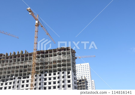 Construction of new residential high-rise buildings. Against the background of a yellow sunset sky. Construction of new residential high-rise buildings. Against the background of a yellow sunset sky. 114816141