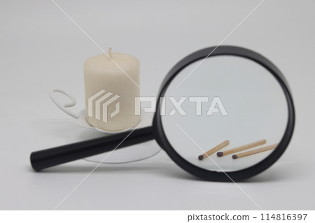 A candle in a white candlestick, matches are visible through a magnifying glass, is it worth burning A candle in a white candlestick, matches are visible through a magnifying glass, is it worth burning 114816397