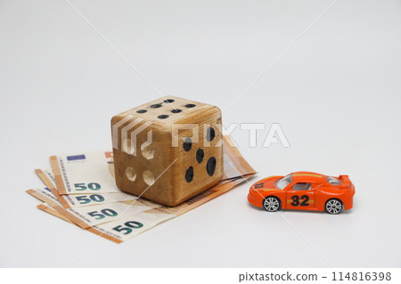 A homemade cube and a toy car lie on banknotes and symbolize motor vehicle insurance. 114816398