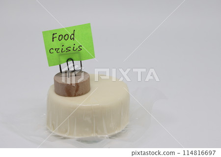 A round piece of cheese in a package and a sticker that says world food crisis. 114816697