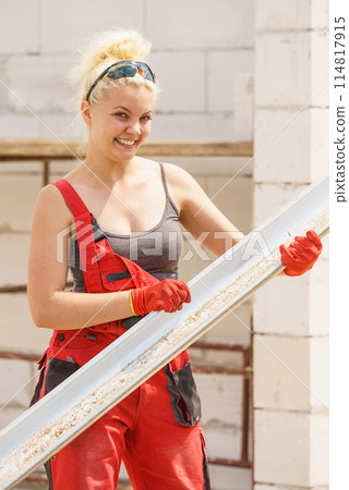 Woman carrying gutter on construction site Woman carrying gutter on construction site 114817915