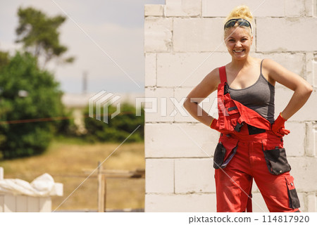 Woman in dungarees working on construction site 114817920