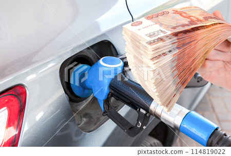 Gasoline pump gun to release fuel into passenger car and stack of russian rubles 114819022