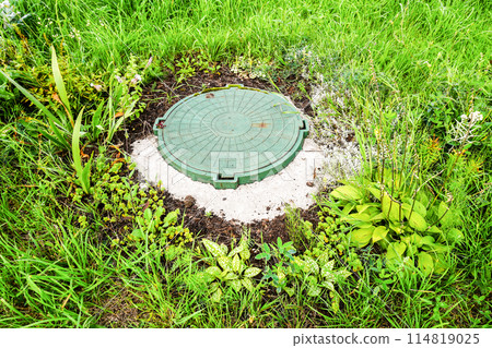 Covered sewer manhole with green plastic cover, sewage system. Sewerage networks. Sanitary sewer system manhole cover Covered sewer manhole with green plastic cover, sewage system. Sewerage networks. Sanitary sewer system manhole cover 114819025