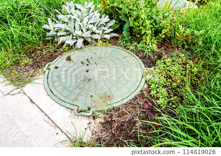 Covered sewer manhole with green plastic cover, sewage system. Sewerage networks. Sanitary sewer system manhole cover 114819026
