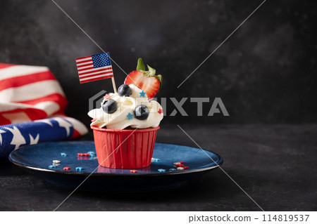 American cupcake with sugar sprinkles as stars and USA flag in blue plate on black background. Dessert for Patriotic Independence Day 4th of July. Copy space 114819537