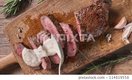 Chef pours pepper sauce on a slices of freshly grilled beef steak 114819558