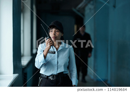 Female guard speaking on walkie-talkie Female guard speaking on walkie-talkie 114819684
