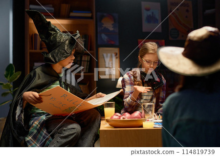 Boy in witch hat and mantle helping girl Boy in witch hat and mantle helping girl 114819739