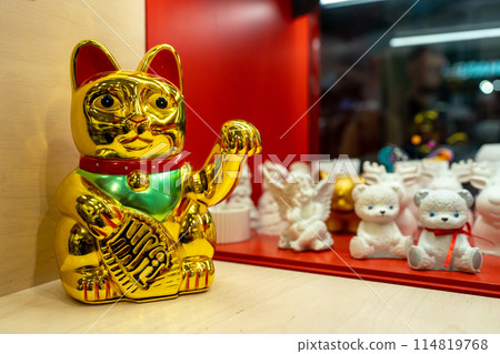 Maneki Neko, Japanese Lucky Cat in a gift shop window. Golden cat brings good luck and wealth closeup 114819768