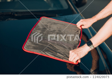 Worker washing car at car wash and wipes vehicle with rag Worker washing car at car wash and wipes vehicle with rag 114820073