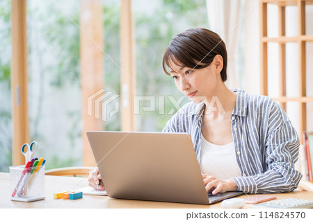 A middle-aged woman who teleworks in the living room. 114824570