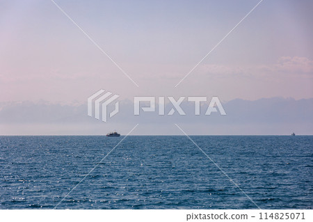 Boats with Kyrgyzstan flag on Issyk-Kul lake at summer day with mountains on horizon. Boats with Kyrgyzstan flag on Issyk-Kul lake at summer day with mountains on horizon. 114825071