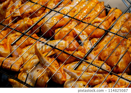 Delicious chicken frying on barbecue grill grate outdoor. Seasoning falling on fresh grilled chicken wings. Summer party food ideas. BBQ Juicy roasting chicken grill legs 114825087