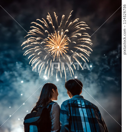 A young couple on a date standing close together looking up at fireworks A young couple on a date standing close together looking up at fireworks 114826786