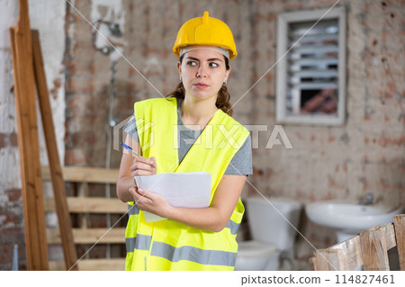 Female civil engineer making notes while controlling construction site Female civil engineer making notes while controlling construction site 114827461