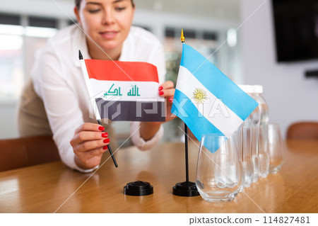 Unrecognizable girl sets midget flags of Argentina and Iraq before international negotiations Unrecognizable girl sets midget flags of Argentina and Iraq before international negotiations 114827481