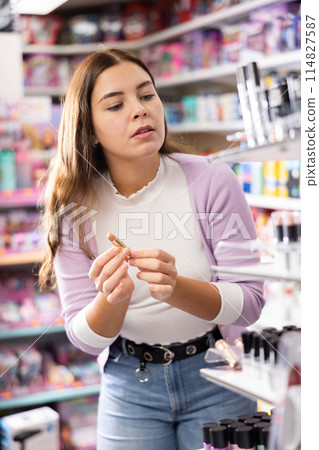Girl buying lipstick or lip gloss in makeup store 114827587