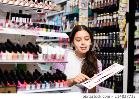 Girl choosing nail polish from color samples in makeup store 114827732