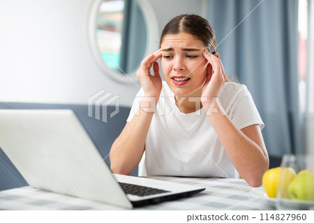 Girl with a headache complains to the doctor on the Internet using laptop 114827960