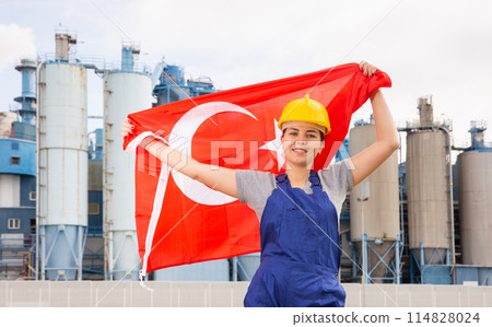 Happy girl in work clothes and hardhat with flag of turkey standing in front of industrial scenery Happy girl in work clothes and hardhat with flag of turkey standing in front of industrial scenery 114828024