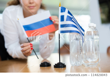 Young female secretary preparing room for international negotiations between greece and russia 114828043