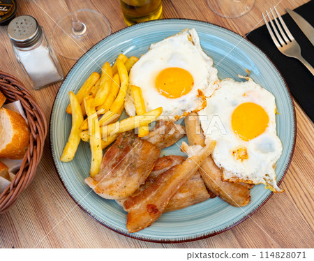 Fried eggs with french fries and streaky side bacon Fried eggs with french fries and streaky side bacon 114828071