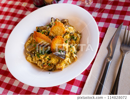 Scrambled eggs with ceps, prawns and caramelized onion 114828072