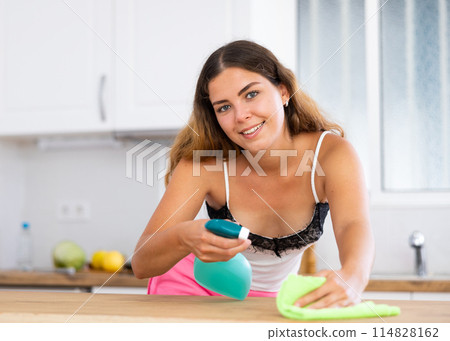 Positive housewife cleans table in home kitchen Positive housewife cleans table in home kitchen 114828162
