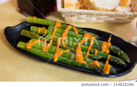 Steamed asparagus under romesk sauce on a black plate 114828166