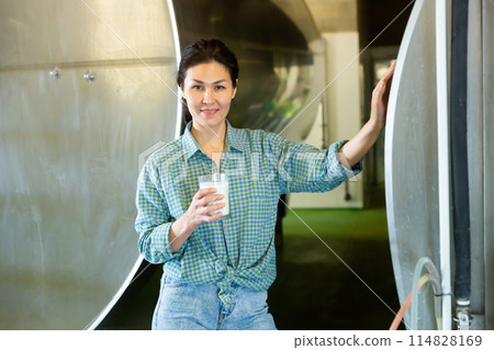 Portrait of a smiling asian woman standing in a dairy farm with a glass of milk 114828169