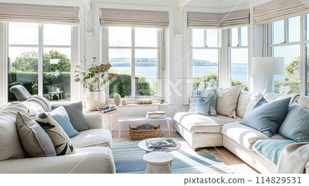 Interior of a living room with white walls, sofa and cushions. Sitting room in coastal cottage with sea view. Luxury lounge room 114829531