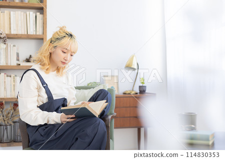 Young woman reading a book in the living room Young woman reading a book in the living room 114830353