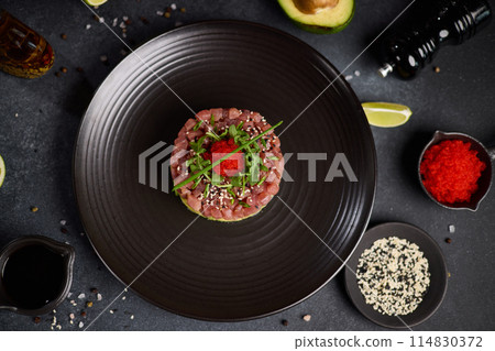 Tuna and avocado tartare on a dark ceramic plate Tuna and avocado tartare on a dark ceramic plate 114830372