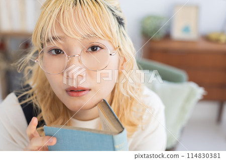 Young woman reading a book in the living room Young woman reading a book in the living room 114830381