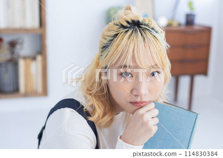 Young woman reading a book in the living room Young woman reading a book in the living room 114830384