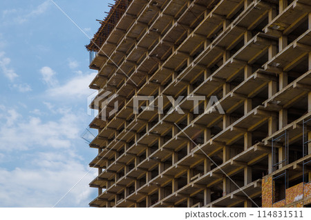 High-rise apartment building under construction against a blue sky with simple urban design 114831511