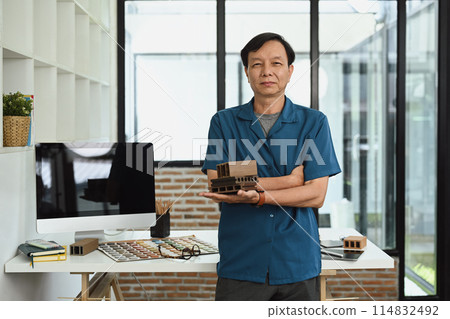 Portrait of smiling senior architect standing by working desk in creative office 114832492