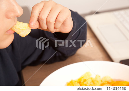 Caucasian person in navy blue t-shirt holding plate full of potato chips, young male eating potato chips 114834668