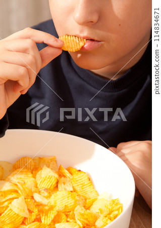 Caucasian person in navy blue t-shirt holding plate full of potato chips, young male eating potato chips 114834671