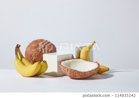 Two rectangular white empty platform in different size placed in the middle and surrounded by fresh banana and coconut on white minimal background. Copy space for text, front angle shot Two rectangular white empty platform in different size placed in the middle and surrounded by fresh banana and coconut on white minimal background. Copy space for text, front angle shot 114835242