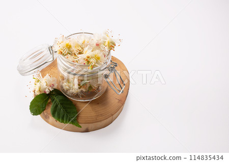 Tincture of horse chestnut flowers in a jar. Homemade herbal tincture. Hair treatment concept. Flat lay 114835434