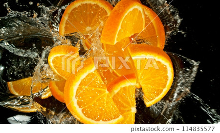 Freeze Motion of Flying Orange Slices into Water, Black Background. Freeze Motion of Flying Orange Slices into Water, Black Background. 114835577