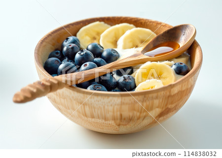 Blueberries, banana bites with greek yoghurt, granola and honey in bowl 114838032